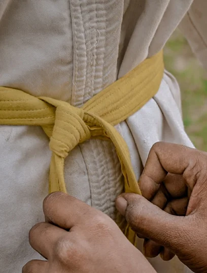 Gros plan de mains nouant une ceinture de niveau débutant.